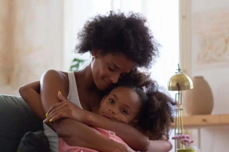 A mother and daughter sharing a warm, loving hug indoors.
